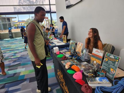 Student attending career fair visiting booth and talking to rep.